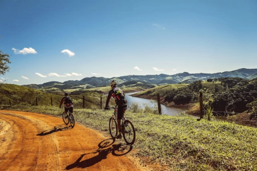 Two bicyclists passing the road near a river