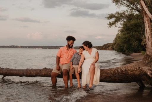 A family sitting on a log on the shore